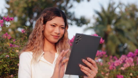 young woman using tablet outdoors in a garden