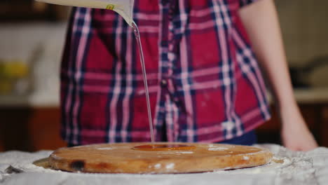 a woman pours a vegetable oil on a board where she begins to knead a dough for pizza 4k video