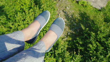 pies femeninos están volando sobre el precipicio cubierto de bosque yendo en el remonte en el marco que