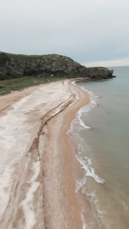 vista aérea de una playa con una persona caminando por la arena