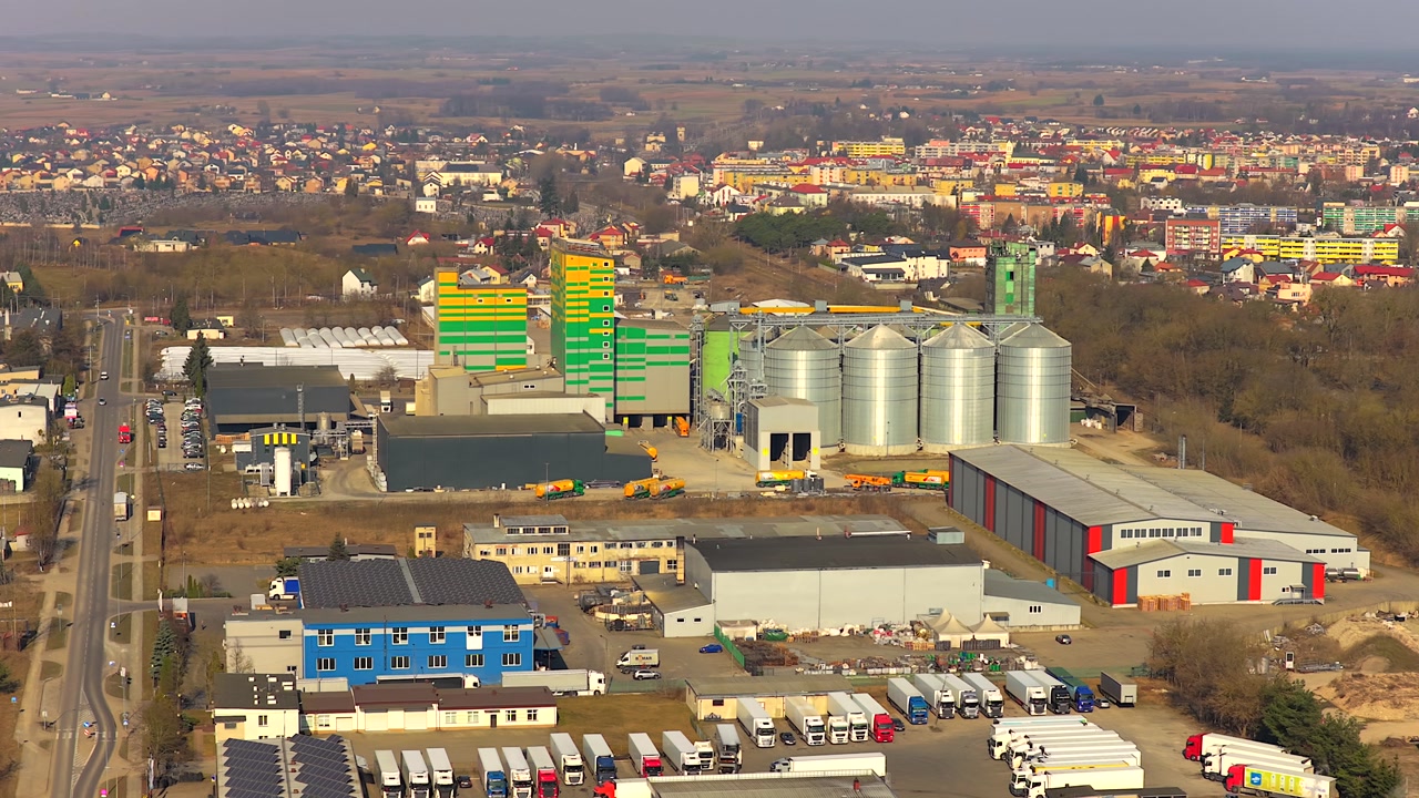 Aerial orbiting shot showing a modern livestock feed production factory with large steel silos and a logistics center in grajewo, poland