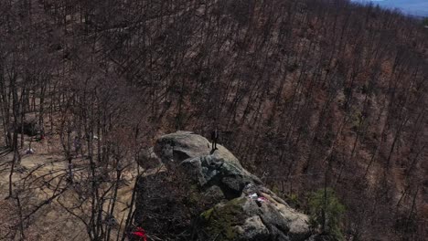 orbiting drone shot of a tourist standing on top of a natural rock formation of skribina, a place famous for its miraculous healing powers at the rhodope mountains in bulgaria.
