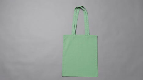 primer plano de una bolsa verde sobre un fondo gris, con espacio de copia, cámara lenta