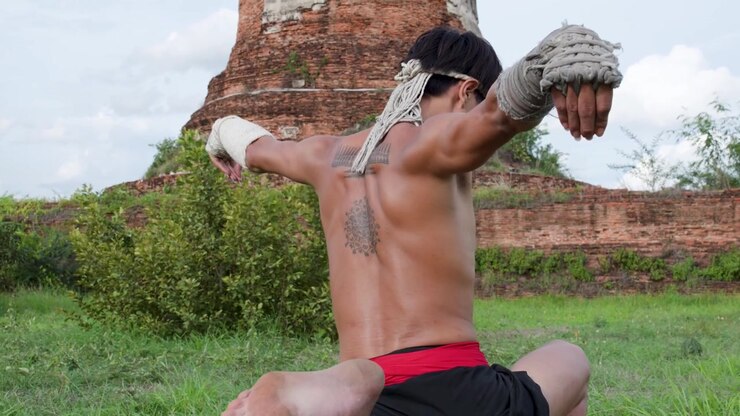 Combattente di Muay Thai che esegue il tradizionale rituale Wai Kru in un antico tempio