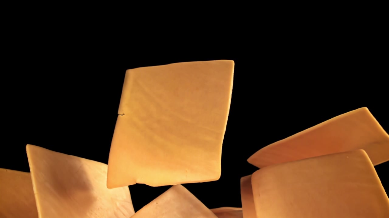 Slow Motion Cheese Slices Falling on Black Background