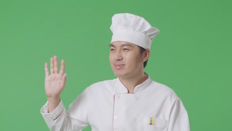 asian man chef walking and waving hand in the green screen background studio