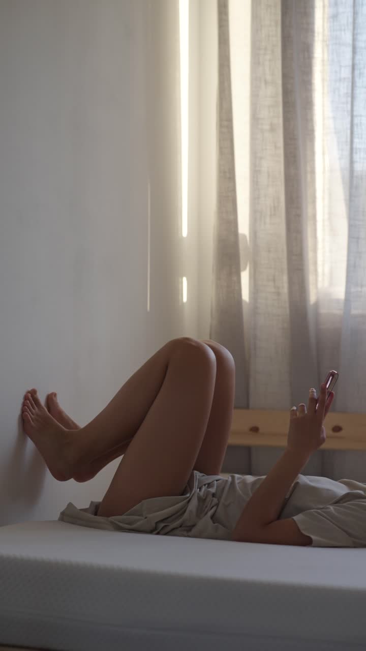 Donna che si rilassa sul letto con lo smartphone