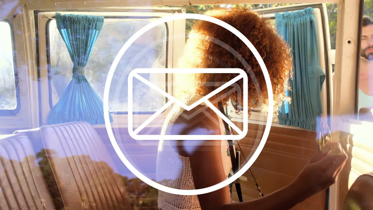 Sitting in van, woman with curly hair looking at large email animation icon