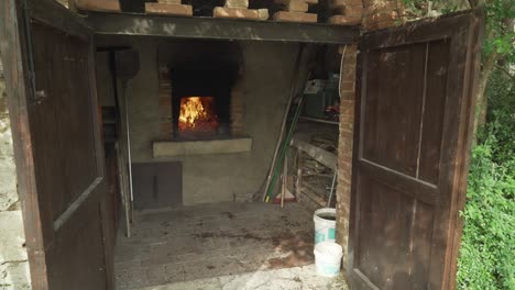 rustic outdoor brick oven with open doors and burning fire