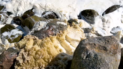 frothy water sloshes against the stones