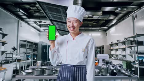 chef sosteniendo un teléfono con pantalla verde en una cocina
