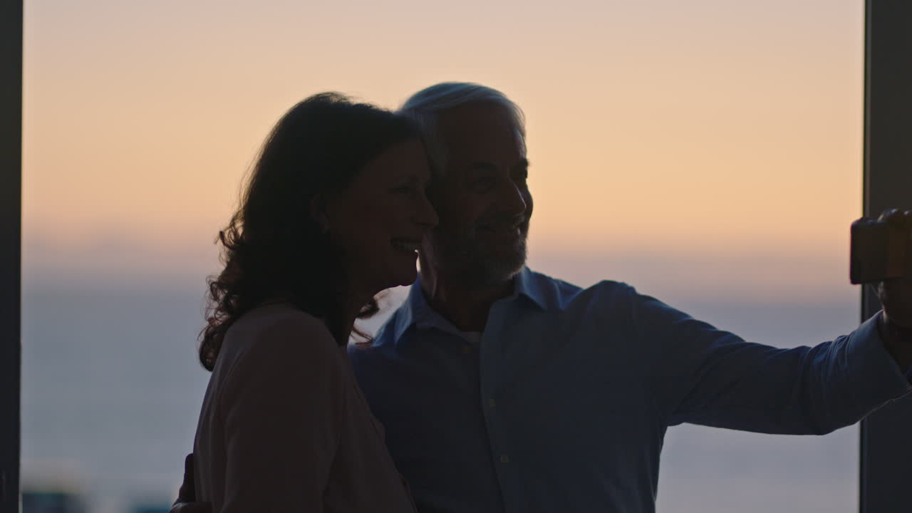 happy old couple taking photo using smartphone hugging enjoying successful retirement sharing vacation on social media at sunset