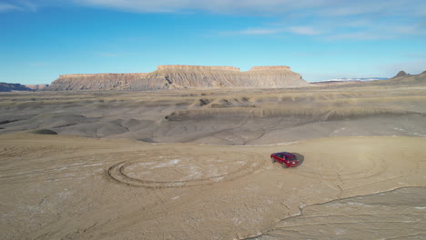 drone shot of red van moving off road in desert landscape of utah usa