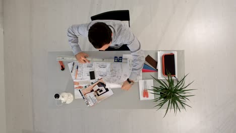 el arquitecto está trabajando en el plan de construcción con una regla. vista superior