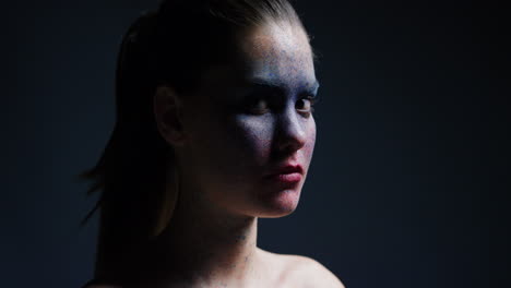 portrait beautiful woman wearing blue face paint makeup looking up exotic body art on attractive female performer creative expression light fading in dark background