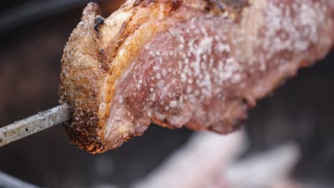 Close-up-of-picanha-slowly-cooking-over-wood-fire-BBQ-pit