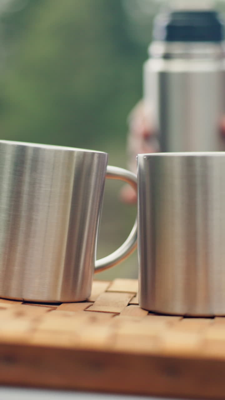 Pouring water into metal mugs on a picnic
