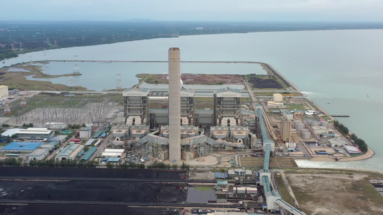 toma aérea industrial de la cuenca carbonífera costera, central eléctrica de carbón ultrasupercrítica con humo saliendo de la chimenea ubicada en la terminal a granel lekir jalan, teluk rubiah, manjung, perak, malasia