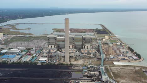 industrial aerial shot of coastal coalfield, ultra-supercritical coal-fired power plant with smokes raising from chimney located at lekir bulk terminal jalan, teluk rubiah, manjung, perak, malaysia