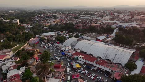 mercado adolfo lópez, cuernavaca, with traffic, market stalls, and cityscape at sunset. backward aerial panoramic shot