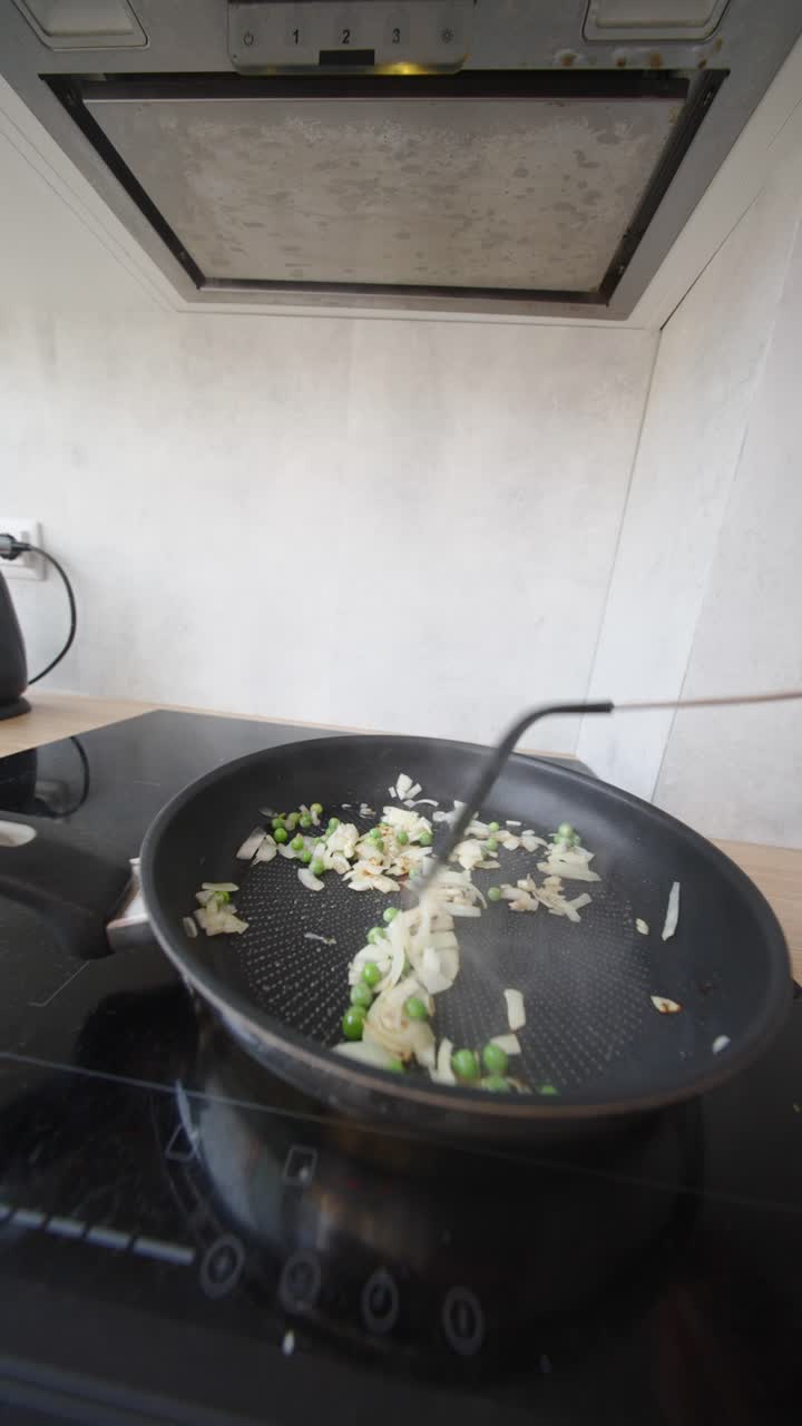 Cooking onions and peas in a pan