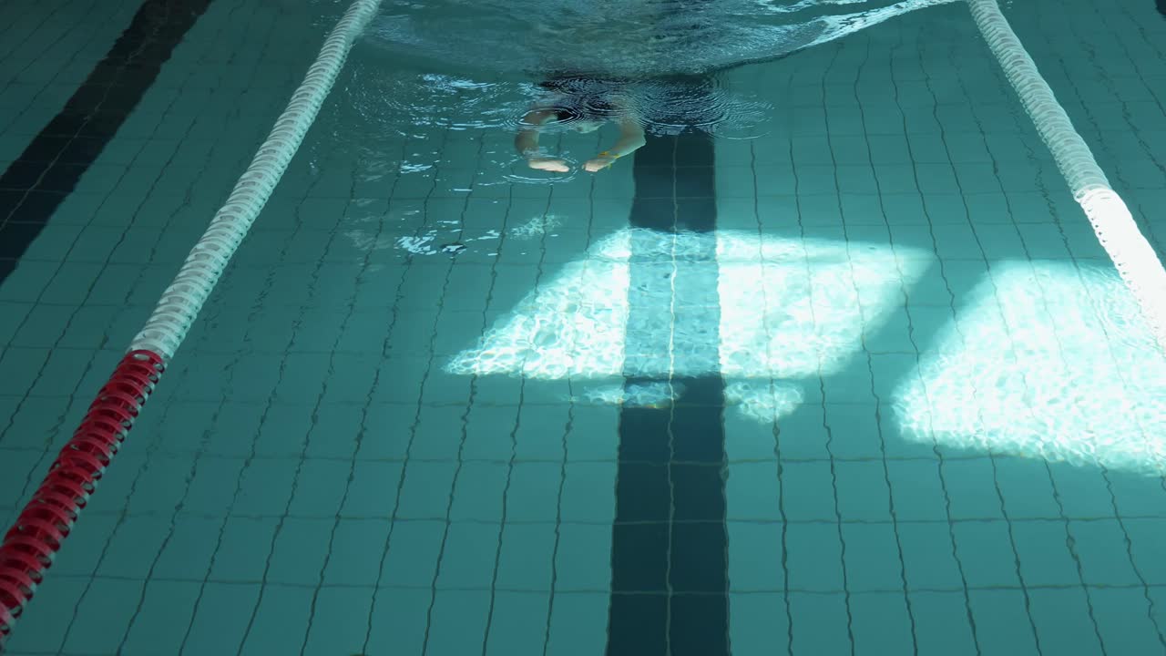 물 위에 자연적인 빛을 는 닫힌 수영장 지역에서 느하게 수영하는 여성 인물을 포착하는 조용한
