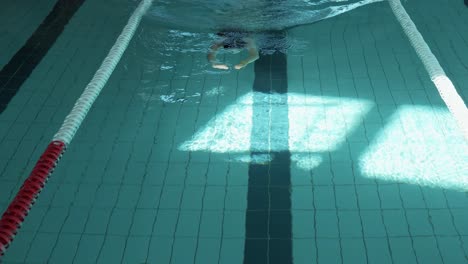 a serene shot capturing a female figure swimming leisurely in an enclosed pool area with natural light casting over the water