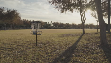 catch camera of a disc golf ace | disc golf basket in the middle of a grassy field