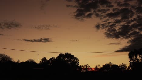 puesta de sol australiana con gran formación de nubes altocúmulos rojos y lapso de tiempo de árboles de goma, maffra, victoria, australia