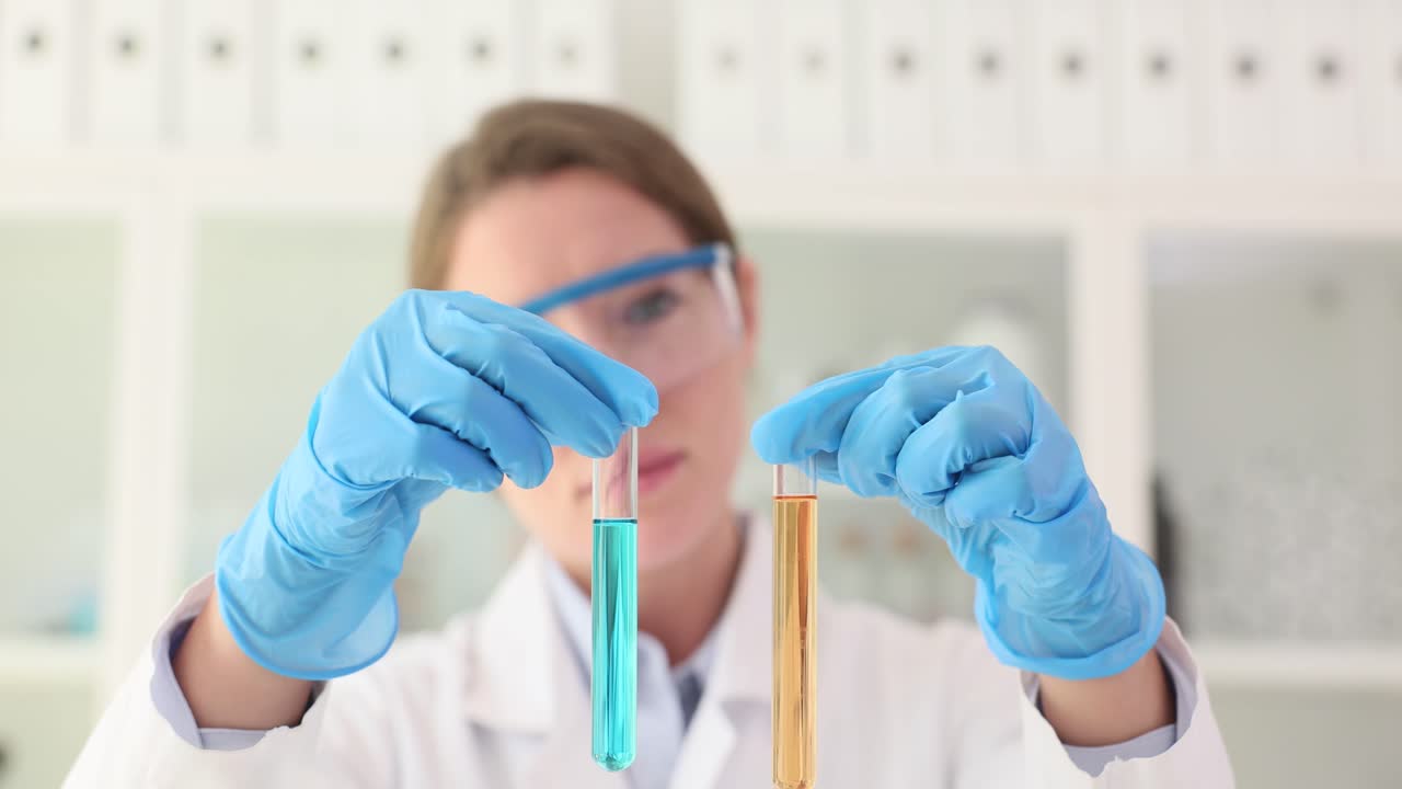 Scientist in lab coat holding two test tubes with colored liquids