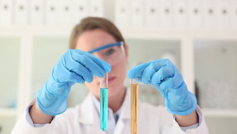 scientist in lab coat holding two test tubes with colored liquids