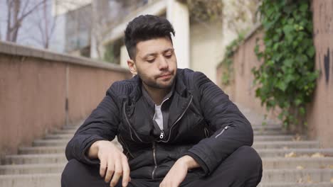 stressful and tired sad man in the city sits on the floor.