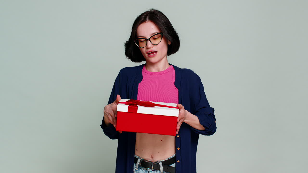 Excited happy woman extending hands forward holding birthday gift box expressing surprise present