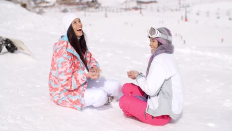 Two-young-female-friends-chatting-in-the-snow