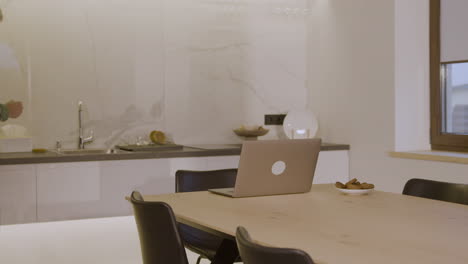 elderly man sitting on chair in kitchen and using laptop computer