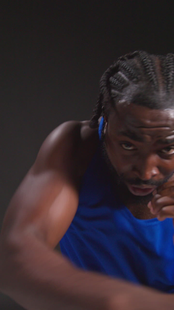 Vertical Video Close Up Studio Portrait Of Male Boxer Training In Gym Sparring Towards Camera And Warming Up Preparing For Fight Against Black Background