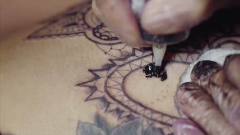 artista del tatuaje aplicando tinta a un diseño de mandala