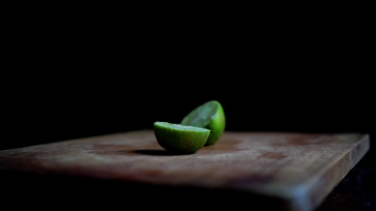 Close up of a lemon being cut in half with a knife on a chopping board