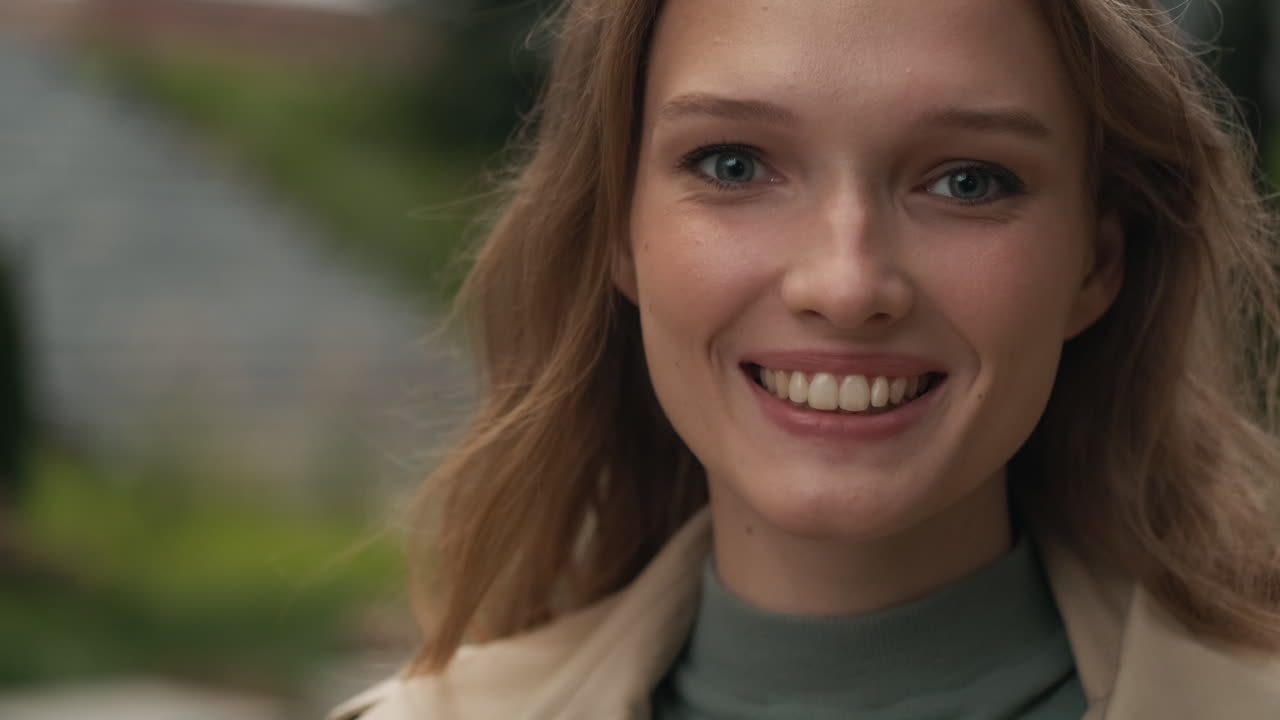 Caucasian woman looking at the camera and smiling outdoors.