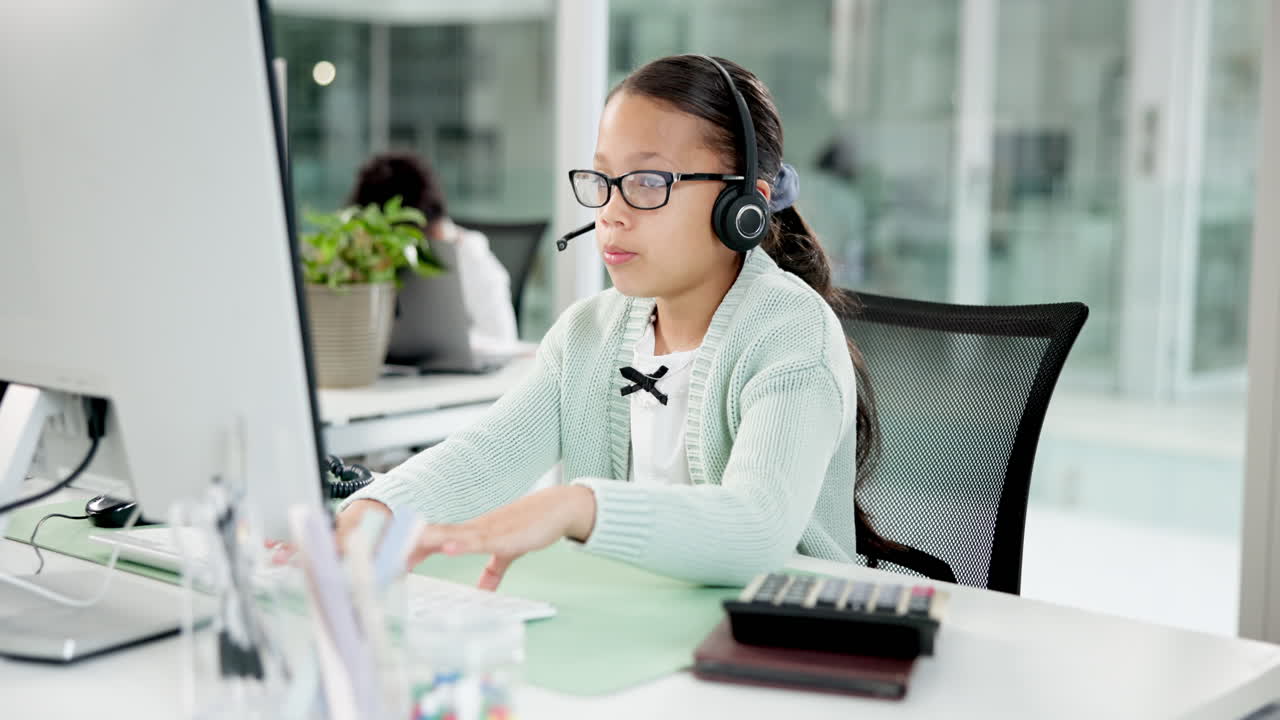 Ung jente med headset som jobber på datamaskin på kontoret