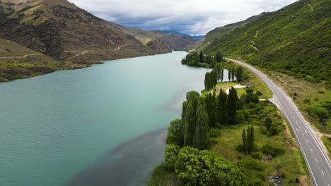 a drone shot made above an asphalt road and a walking trail winding along the fiord nearby the champagne gully freedom camping, new zealand