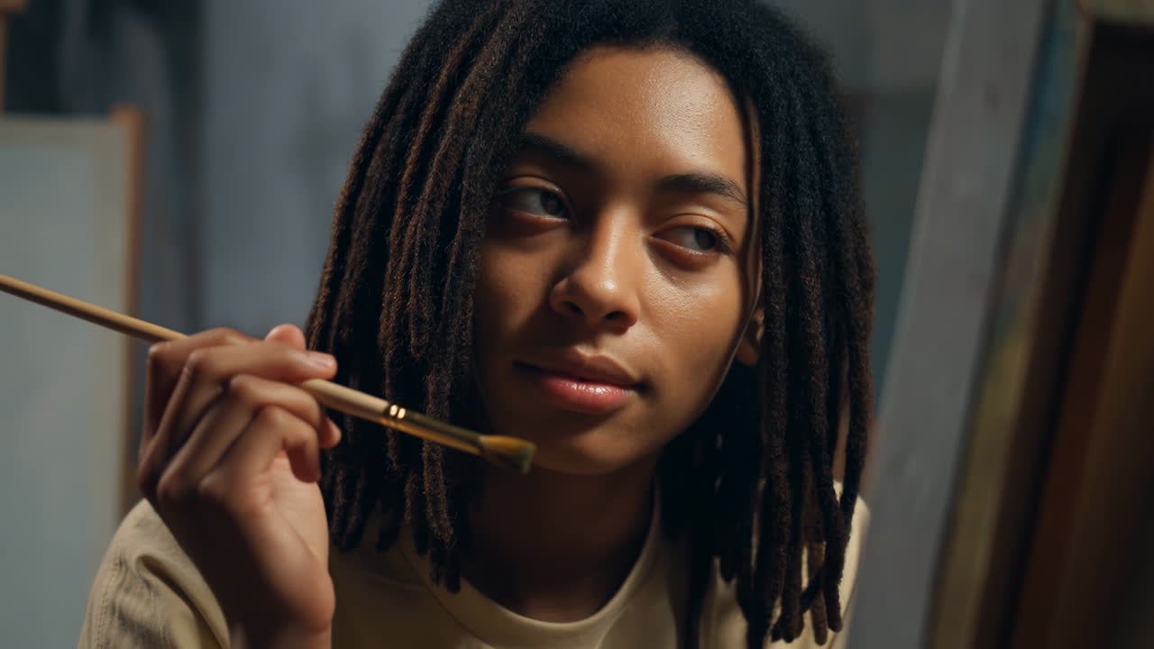 Una donna con i dreadlock che tiene in mano un pennello