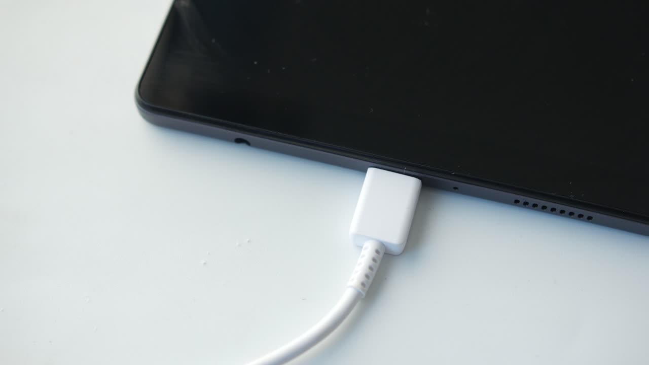 Carregando um tablet digital com um cabo em fundo branco