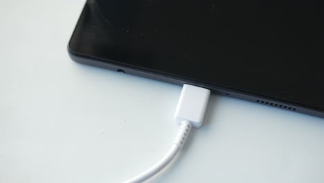 Cargando-Una-Tableta-Digital-Con-Un-Cable-Sobre-Fondo-Blanco.