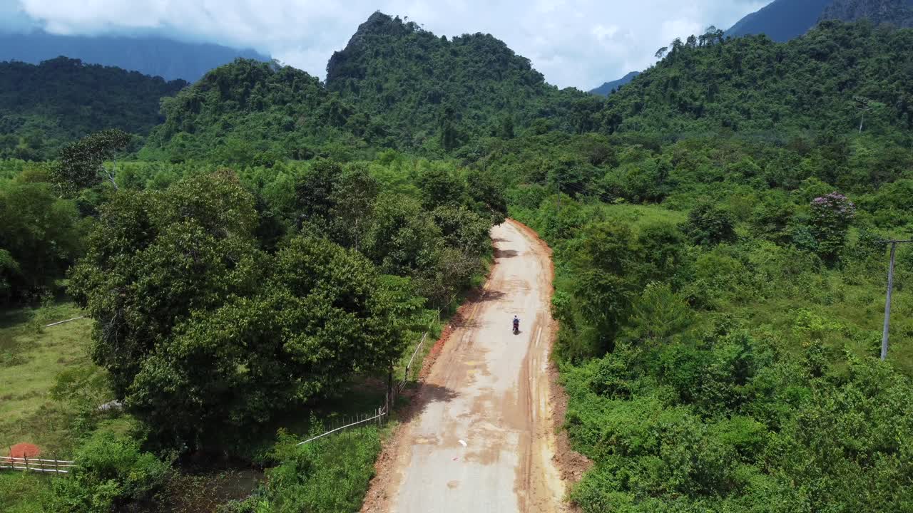 Motociclista che guida tranquillamente lungo una strada sterrata a Naka, Laos