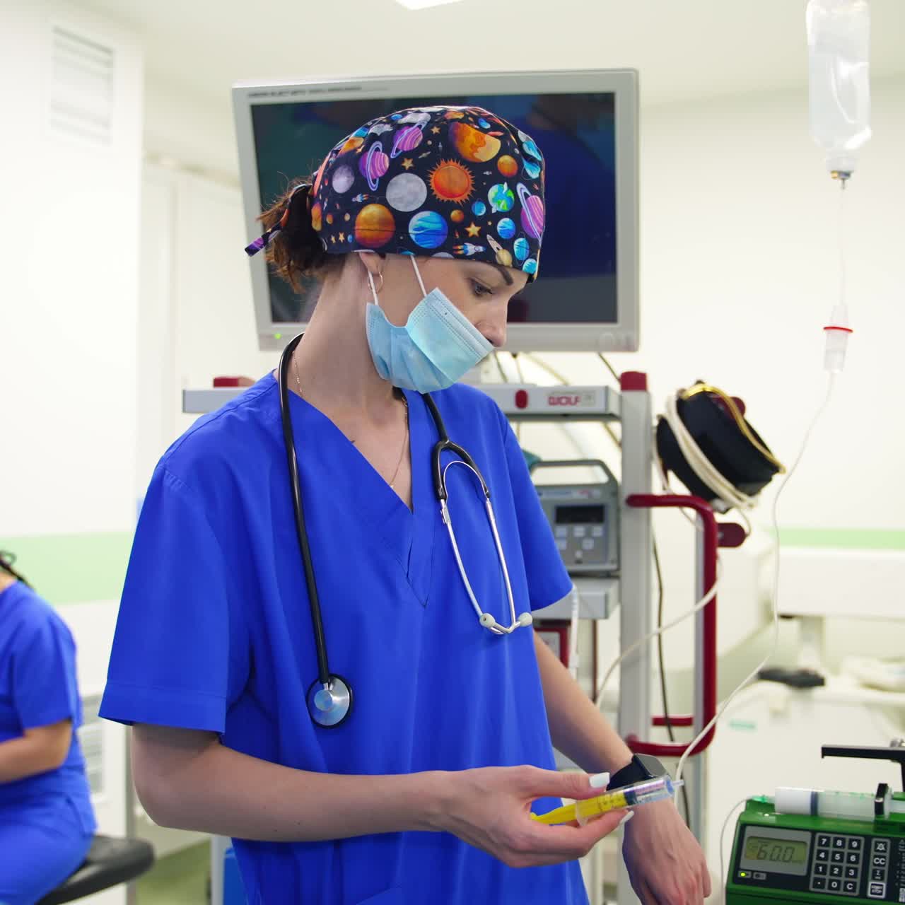 Female doctor in cosmic cap and mask, stethoscope on her shoulders holding a syringe. Medic sets the equipment holding a thin tube in her hand