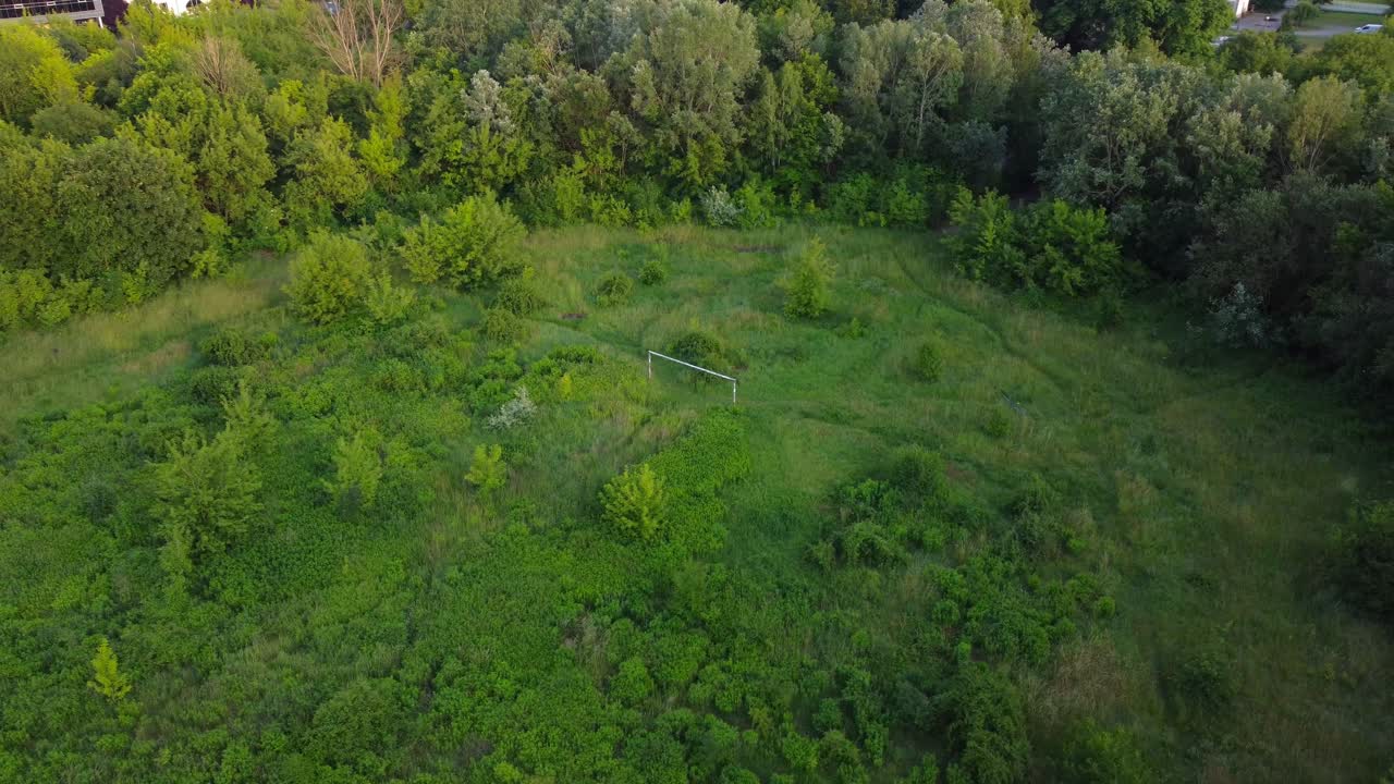Aerial drone view of overgrown football pitch and goalpost in abandoned Edmund Szyc Stadium
