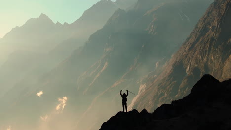 a gliding drone shot captures the silhouette of a male tourist entering the majestic landscape of snow-capped himalayas in langtang national park, nepal, during the golden hour of sunset.