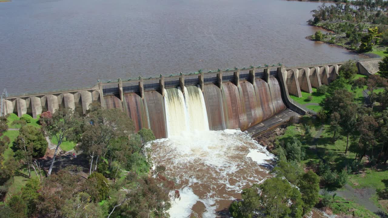 Rising and panning down aerial footage of water being released from Lauriston Reservoir, in central Victoria. October 2022.
