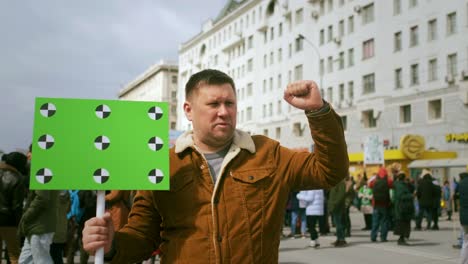 riot activist holds green chroma key banner. blank, empty place for text, logo.